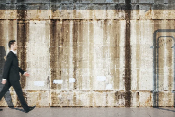 Businessman walking near loft style concrete grunge wall. — 图库照片