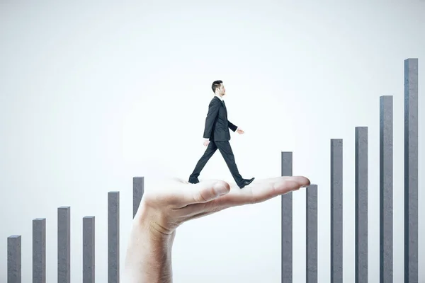 Mão ajuda um homem de negócios a subir em um gráfico de negócios nas costas brancas — Fotografia de Stock