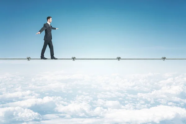 Бизнесмен ходит по веревке на голубом фоне неба — стоковое фото