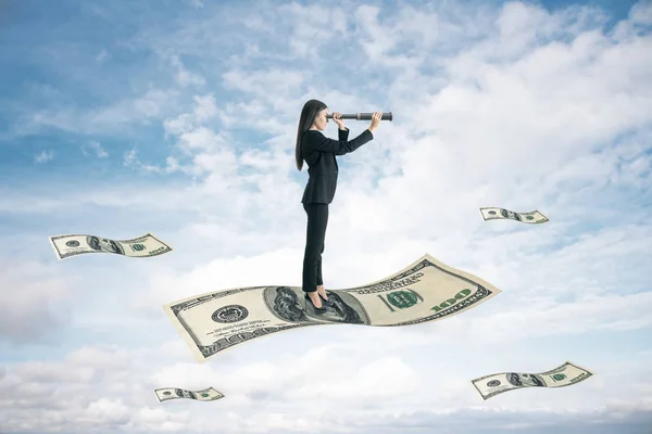 女商人拿着望远镜站在钞票上 望着蓝天 企业与挑战概念 — 图库照片