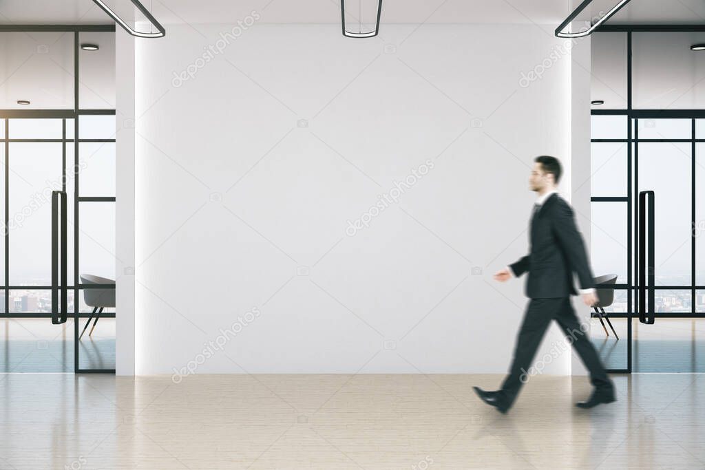 Businessman walking in meeting room with blank white wall. Occupation and worker concept.