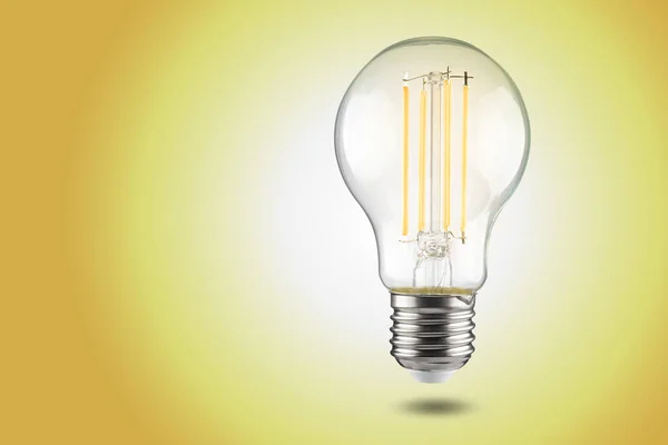 filament LED light bulb bulb with e27 cap on a yellow background.