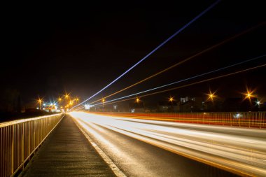 Gece vakti uzun pozlu otoban köprüsü, şehrin ışıkları ve hızlı arabalarla