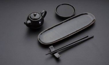 Siyah temiz yemekler suşi ve rulo için ayarlayın. Japon yemek çubukları, plaka, siyah masanın üzerinde uçan daire.