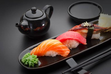 Ton balığı, somon ve yılan balığı suşi nigiri siyah masada