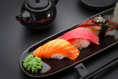 Ton balığı, somon ve yılan balığı suşi nigiri siyah masada