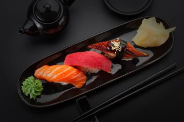 Ton balığı, somon ve yılan balığı suşi nigiri siyah masada