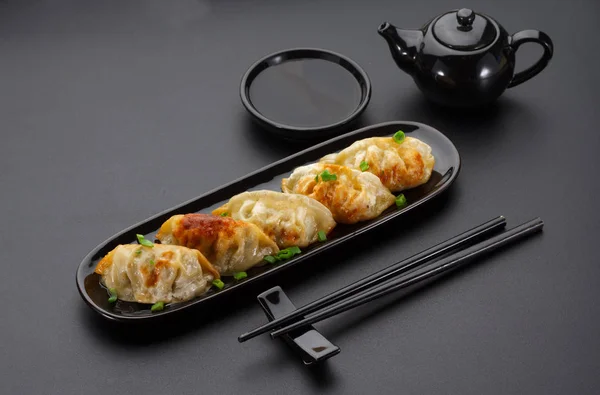 Un plato de gyoza japonesa sobre fondo negro —  Fotos de Stock