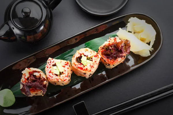 Sushi with shrimp and red tobiko in mamenori on a black plate — Stock Photo, Image
