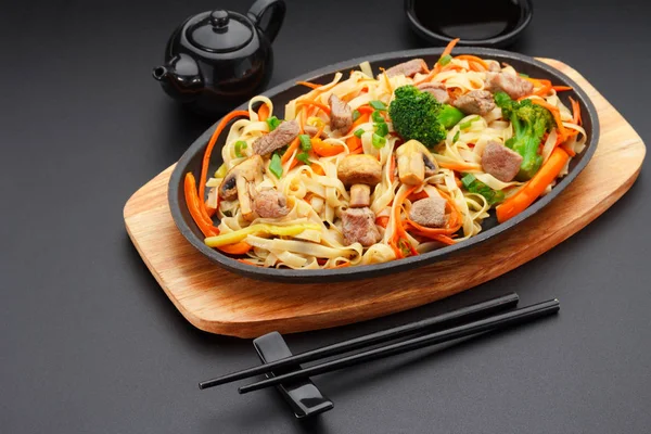 Asia food. Udon noodles with pork on a black table. — Stock Photo, Image