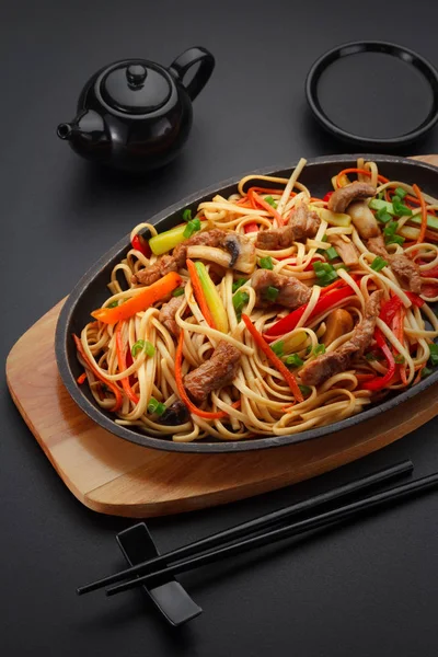 Comida asiática. Macarrão Udon com carne de porco na mesa preta . — Fotografia de Stock