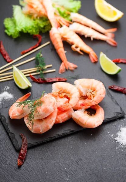 Camarões cozidos saborosos com espetos em uma chapa de pedra com limão e salada . — Fotografia de Stock