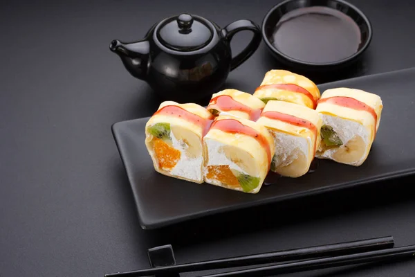 Sweet sushi roll in mamenori with kiwi, banana, orange and mascarpone on a stone plate. — Stock Photo, Image