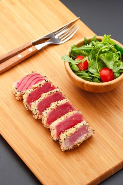 Bir ahşap tahta üzerinde ızgara ton balığı filetosu.