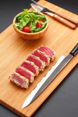 Bir ahşap tahta üzerinde ızgara ton balığı filetosu.