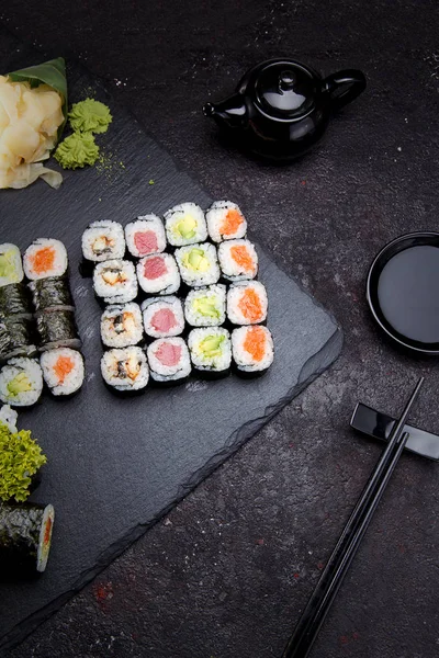 Japanese cuisine. Sushi roll with fresh ingredients on a stone plate and background.