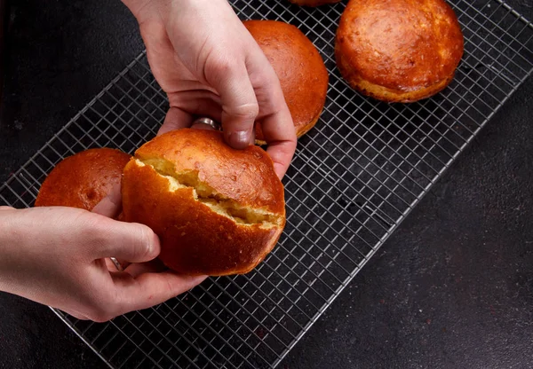 Tasty fresh newly-baked buns on a iron grid over wooden background — Stock Photo, Image