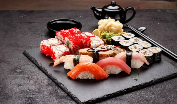Japanese cuisine. Sushi set on a stone plate and concrete background. — Stock Photo, Image