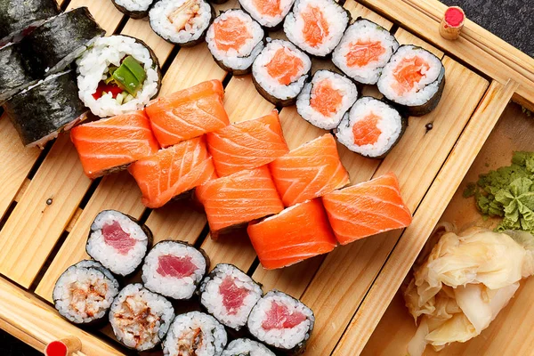 Japanese cuisine. Sushi set on a wooden plate and dark concrete background. — Stock Photo, Image