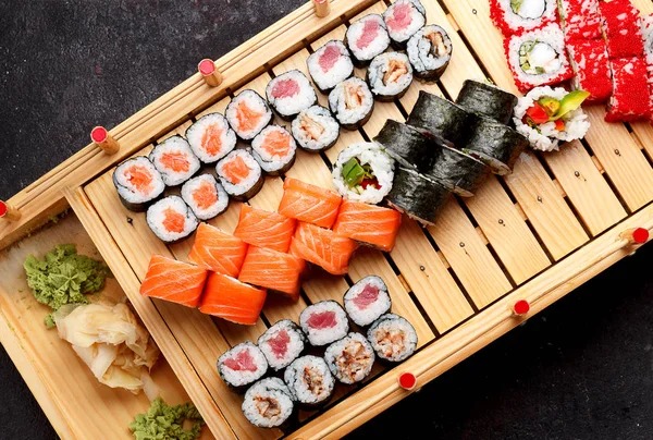 Japanese cuisine. Sushi set on a wooden plate and dark concrete background.