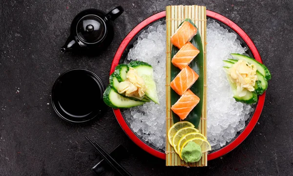 Суши из лосося на бамбуковом листе и льду на темно-бетонном фоне — стоковое фото