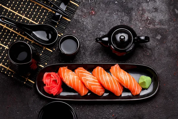 Japanese cuisine. Salmon sushi (nigiri) on a black plate and dark concrete background. — Stock Photo, Image