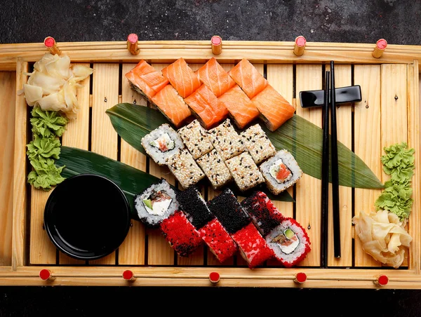 Japanese cuisine. Sushi set on a wooden plate and dark concrete background.