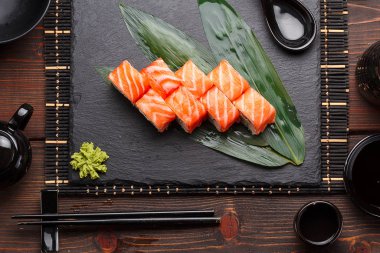 Somon suşi roll bir taş plaka ve ahşap arka plan.