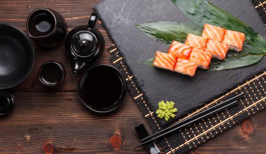 Somon suşi roll bir taş plaka ve ahşap arka plan.