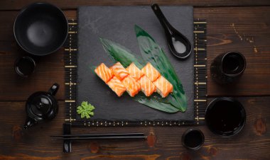 Somon suşi roll bir taş plaka ve ahşap arka plan.