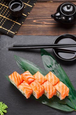 Somon suşi roll bir taş plaka ve ahşap arka plan.