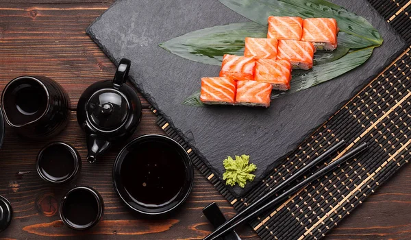 Somon suşi roll bir taş plaka ve ahşap arka plan.