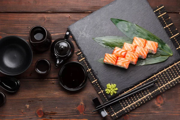 Somon suşi roll bir taş plaka ve ahşap arka plan.