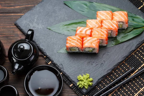 Lax sushi rulle på en sten tallrik och trä bakgrund. — Stockfoto