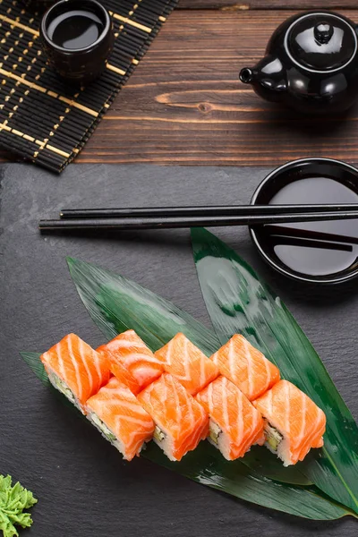 Somon suşi roll bir taş plaka ve ahşap arka plan.