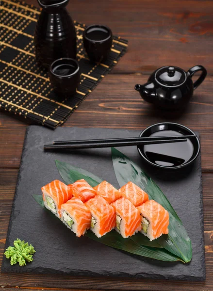 Lax sushi rulle på en sten tallrik och trä bakgrund. — Stockfoto