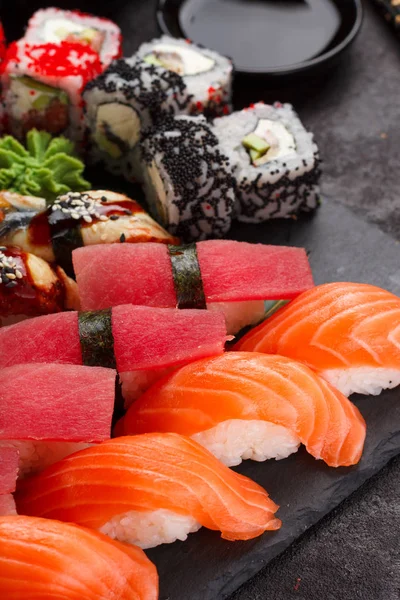 Cozinha japonesa. Sushi definido em uma placa de pedra e fundo de concreto preto . — Fotografia de Stock