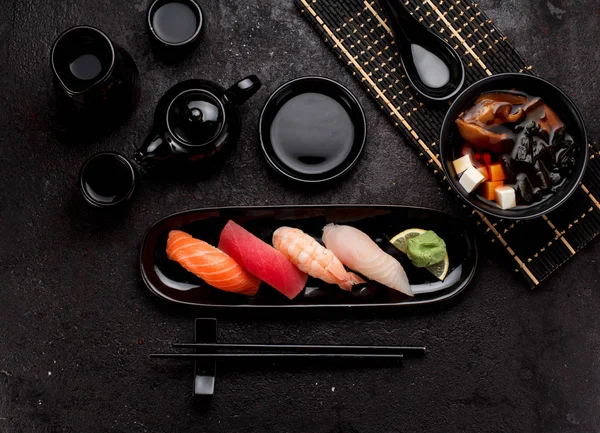 Sushi, meg egy fekete lemezt, és miso leves, mint sötét konkrét háttér — Stock Fotó