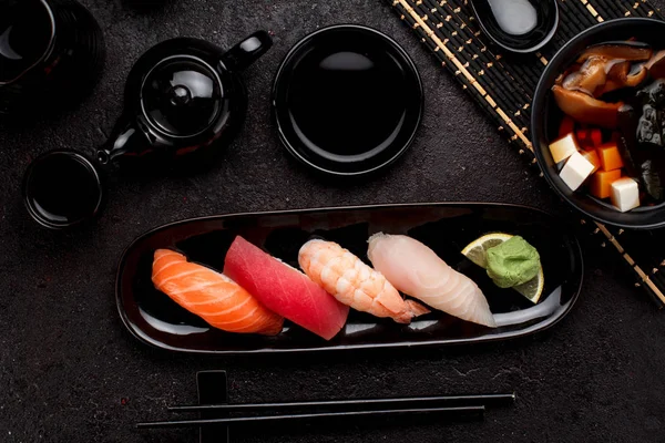 Sushi set on a black plate and miso soup over dark concrete background — Stock Photo, Image