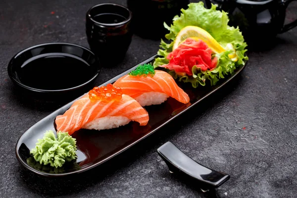 Bir siyah plaka ve beton koyu arka plan üzerinde Soya soslu somon suşi.