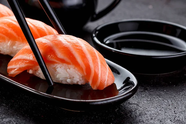 Bir siyah plaka ve beton koyu arka plan üzerinde Soya soslu somon suşi.