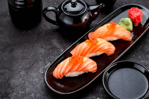 Bir siyah plaka ve beton koyu arka plan üzerinde Soya soslu somon suşi.