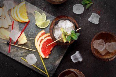 Buz ve taze meyve (greyfurt, kivi, portakal) ve beton arka plan üzerine nane ile Hindistan cevizi.