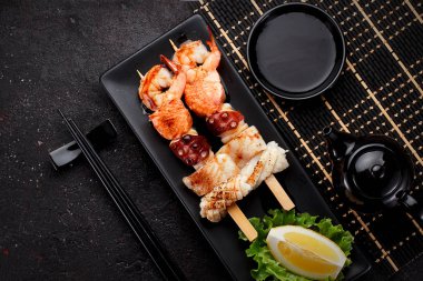 Lezzetli deniz ürünleri şiş ve beton koyu arka plan üzerinde Soya soslu