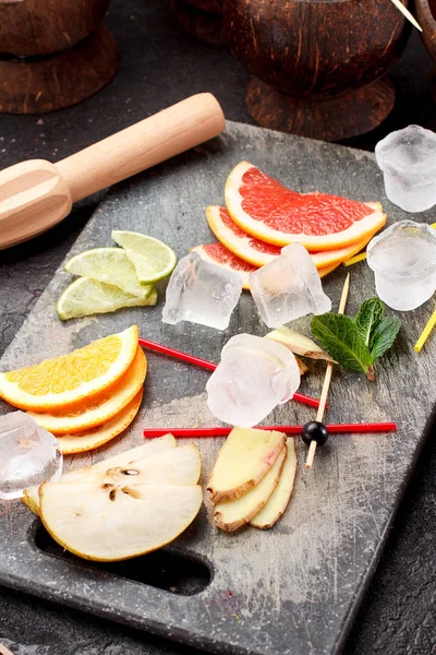 Coconut with ice and fresh fruits (grapefruit, kiwi, orange ) and mint over concrete background. — Stock Photo, Image