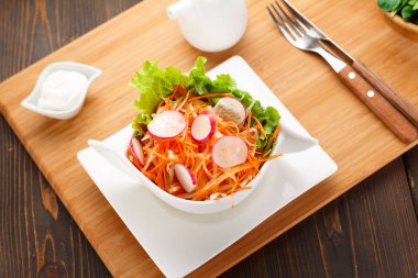 bir beyaz tabak, ahşap levha ve arka plan üzerinde sebze salatası.