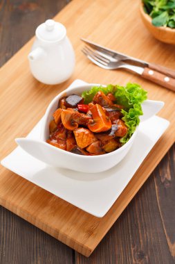 Kızarmış yağlı mantar soslu beyaz tabak, ahşap tahta ve arka plan.