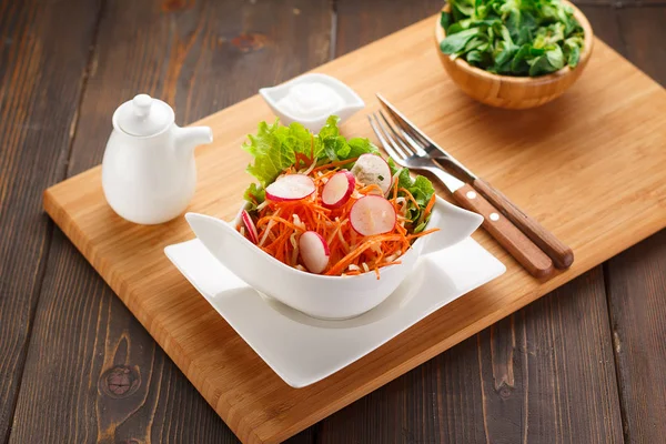 Salade de légumes sur une assiette blanche, planche en bois et fond . — Photo