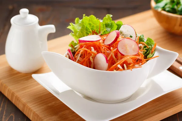 Ensalada de verduras en un plato blanco, tablero de madera y fondo . —  Fotos de Stock