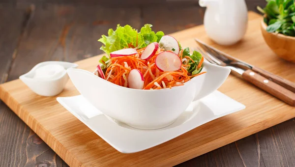 Salade de légumes sur une assiette blanche, planche en bois et fond . — Photo